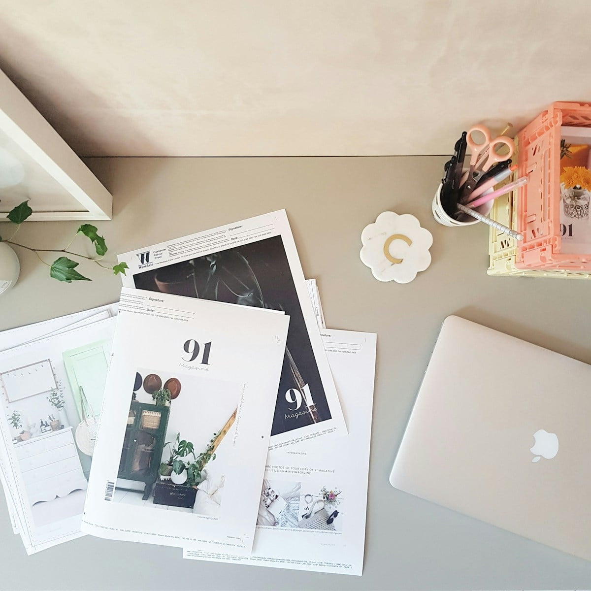 An overhead photo of print outs, a Macbook, writing tools