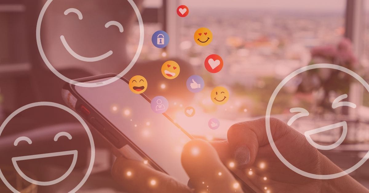 Emojis for nonprofits blog feature image of a hand holding a mobile phone with emoji icons floating around